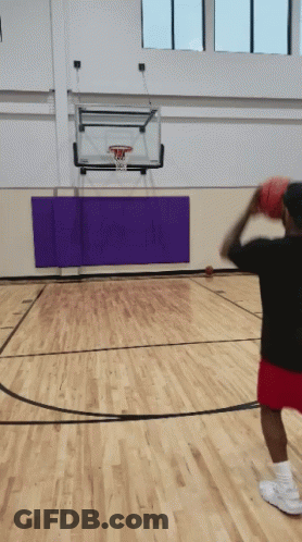 A Man Throws A Basketball In A Gym With A Purple Mat GIF