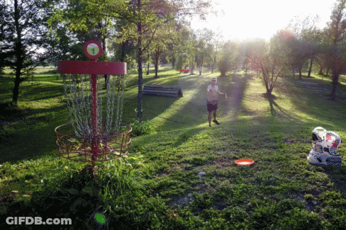 A Man Throws A Frisbee Into A Red Frisbee Golf Basket GIF