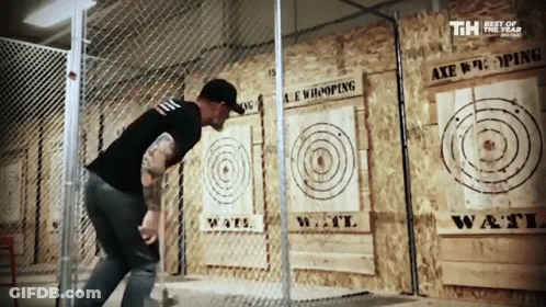 A Man Throws An Axe At A Target That Says Axe Hooping On It GIF