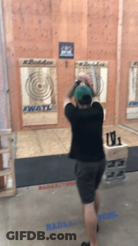 A Man Throws An Axe In Front Of A Wall That Has #Badaxe On It GIF