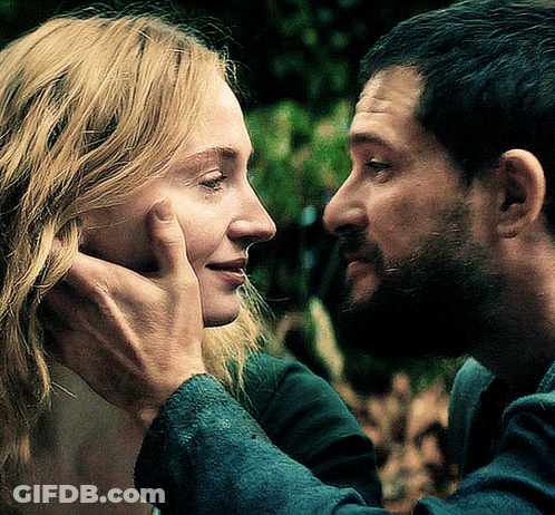 A Man Touches A Woman 'S Face While They Look At Each Other GIF