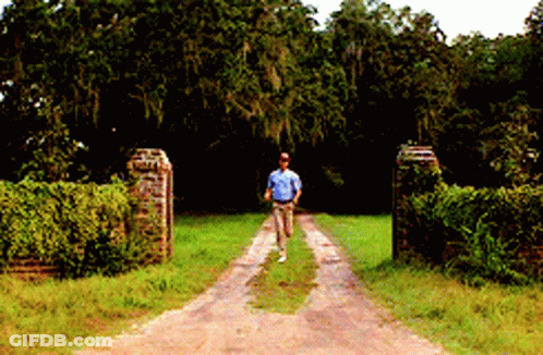 A Man Walking Down A Dirt Road In A Field GIF