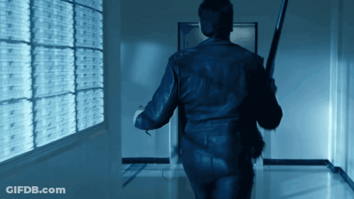 A Man Walking Down A Hallway Holding A Bat GIF