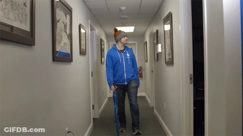 A Man Walking Down A Hallway With A Blue Jacket That Says ' Abercrombie & Fitch ' On The Front GIF