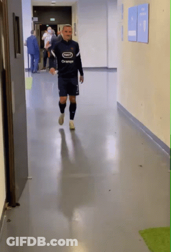 A Man Walking Down A Hallway With A Shirt That Says Orange On It GIF