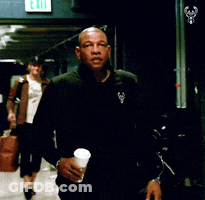 A Man Walking Down A Hallway With An Exit Sign On The Wall GIF