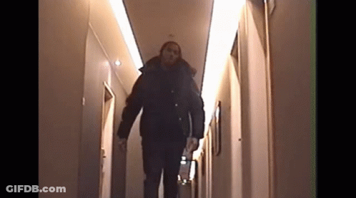 A Man Walking Down A Hallway With The Number 10 On The Wall Behind Him GIF