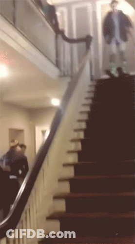 A Man Walking Down A Set Of Stairs In A House GIF