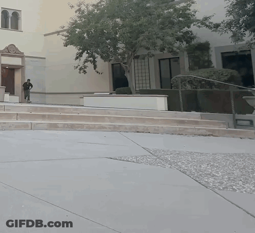 A Man Walking Down A Set Of Stairs In Front Of A Large Building GIF