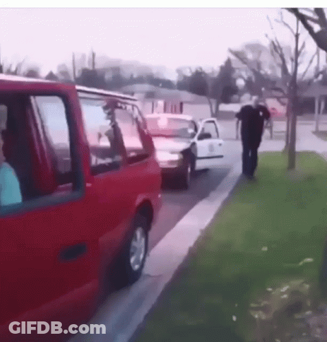 A Man Walking Down A Sidewalk Next To A Red Van GIF