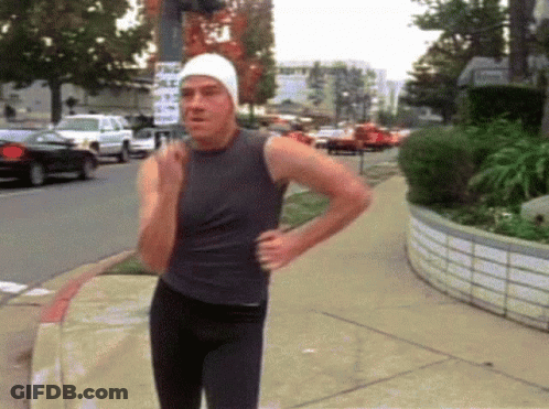 A Man Walking Down A Sidewalk With A Sign That Says " No Parking " GIF