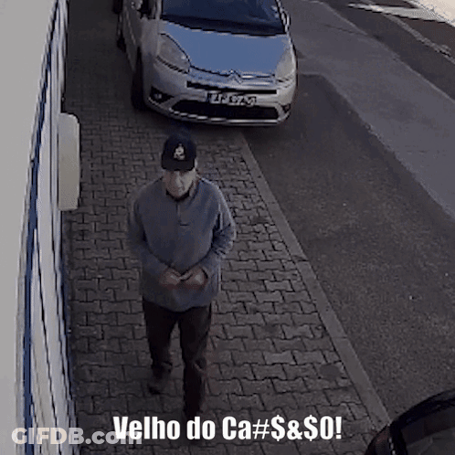 A Man Walking Down A Sidewalk With The Words Velho Do Ca # $ & $ Written Below Him GIF