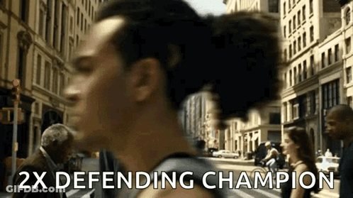A Man Walking Down A Street With The Words " 2X Defending Champion " Written On The Bottom GIF