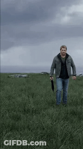 Man Walking With Umbrella In Field GIF
