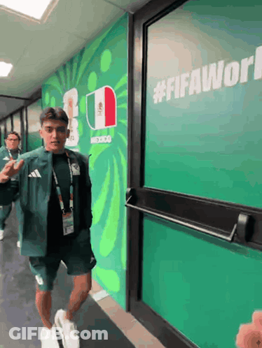 A Man Walking In A Hallway With A Sign That Says #Fifaworld On It GIF
