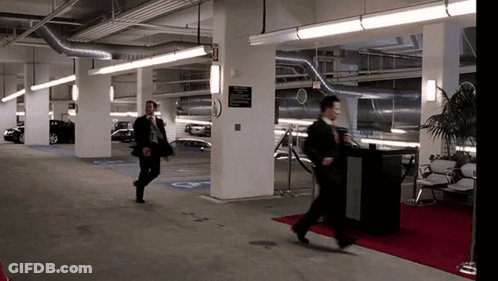 A Man Walking In A Parking Garage With A Sign On The Wall That Says ' Exit ' GIF
