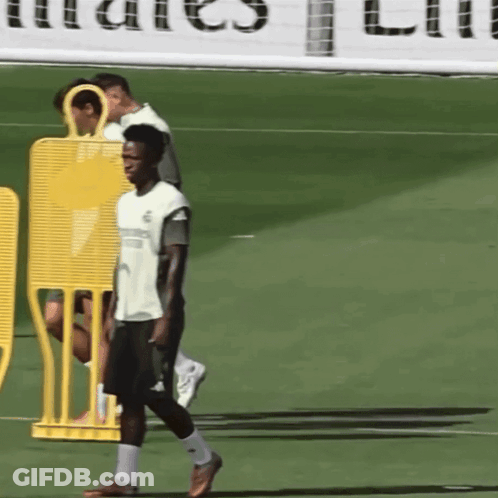 A Man Walking On A Soccer Field In Front Of A Sign That Says ' Emirates ' GIF
