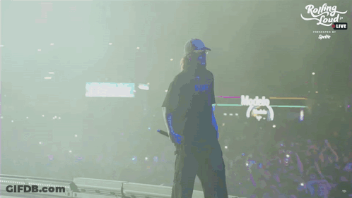 A Man Walking On A Stage With Rolling Loud Written On The Bottom GIF