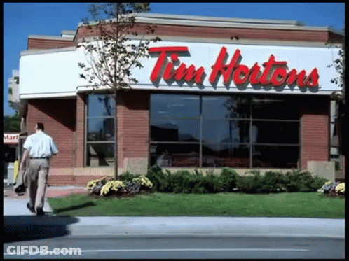 A Man Walks Past A Tim Hortons Store GIF
