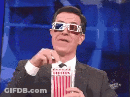 A Man Wearing 3D Glasses Is Holding A Popcorn Box GIF