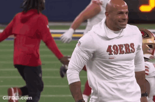 A Man Wearing A 49Ers Shirt Is Smiling On The Field GIF