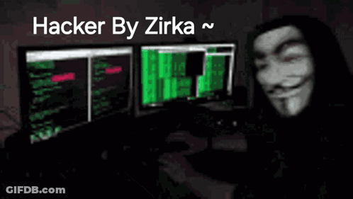 A Man Wearing A Anonymous Mask Is Sitting In Front Of A Computer Monitor . GIF