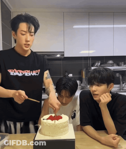 A Man Wearing A Badboy Shirt Is Cutting A Birthday Cake GIF