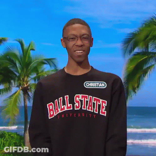 A Man Wearing A Ball State University Sweatshirt Stands In Front Of A Beach GIF