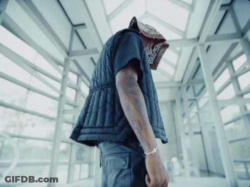 A Man Wearing A Bandana And A Black Vest Looks Down GIF