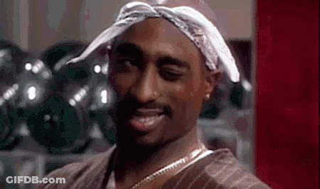 A Man Wearing A Bandana And A Necklace Is Smiling . GIF