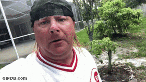 A Man Wearing A Bandana And A White Shirt With A Red And White Striped Collar GIF
