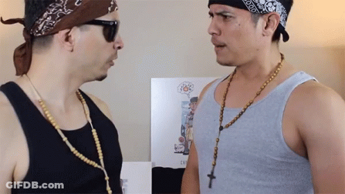 A Man Wearing A Bandana And Sunglasses Talks To Another Man Wearing A Rosary Necklace GIF