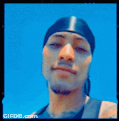 A Man Wearing A Bandana Is Giving A Peace Sign . GIF