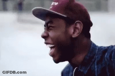 A Man Wearing A Baseball Cap And A Denim Jacket Is Smiling . GIF