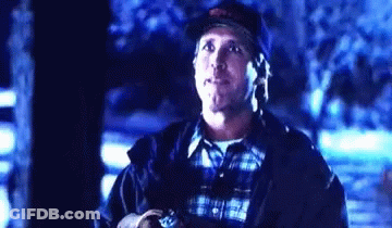 A Man Wearing A Baseball Cap And A Plaid Shirt Is Standing In The Dark Looking Up . GIF