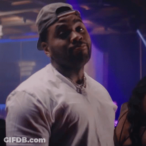 A Man Wearing A Baseball Cap And A White Shirt Is Looking At The Camera GIF