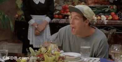 A Man Wearing A Baseball Cap Is Sitting At A Table With Plates Of Food And Glasses Of Water . GIF