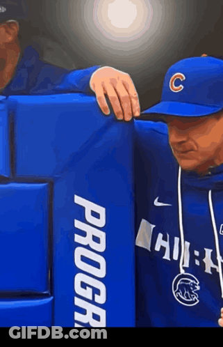 A Man Wearing A Baseball Cap With The Letter C On It Leans On A Blue Progear Block GIF