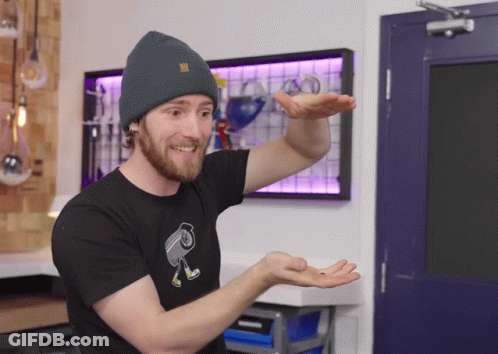 A Man Wearing A Beanie And A Black T-Shirt With A Camera On It GIF