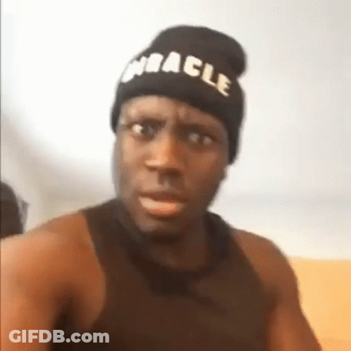 A Man Wearing A Beanie And A Black Tank Top Is Making A Funny Face . GIF