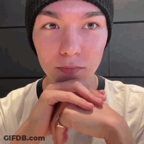 A Man Wearing A Beanie And A Ring Is Looking At The Camera . GIF