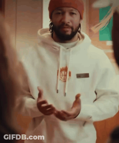 A Man Wearing A Beanie And A White Hoodie With The Letter B On The Front GIF
