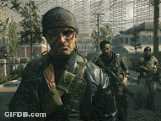 A Man Wearing A Beanie And Glasses Is Standing In Front Of A Group Of Soldiers GIF