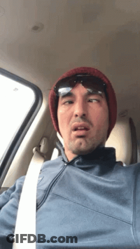 A Man Wearing A Beanie And Sunglasses Is Sitting In The Driver 'S Seat Of A Car GIF