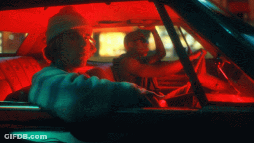 A Man Wearing A Beanie Is Driving A Car With A Red Roof GIF
