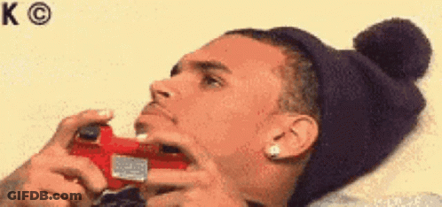 A Man Wearing A Beanie Is Holding A Video Game Controller GIF