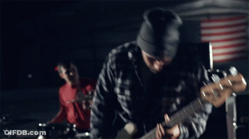 A Man Wearing A Beanie Is Playing A Guitar GIF