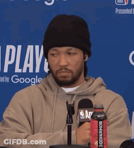 A Man Wearing A Beanie Stands In Front Of A Microphone Holding A Bottle Of Bodyarmor GIF