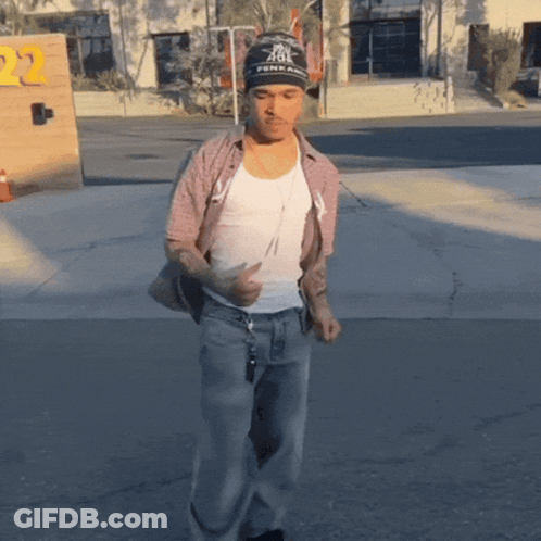 A Man Wearing A Beanie That Says Fenix On It Is Walking Down The Street GIF
