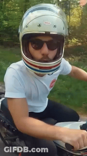 A Man Wearing A Bell Helmet Rides A Motorcycle GIF